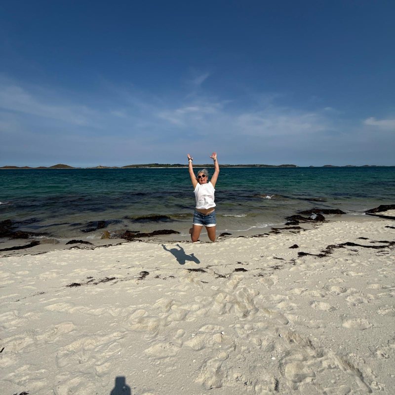 Vicky jumping for joy on an empty white-sand beach